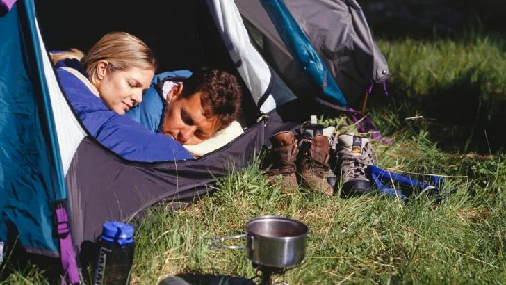 Couple sleeping through sunrise in blackout tent