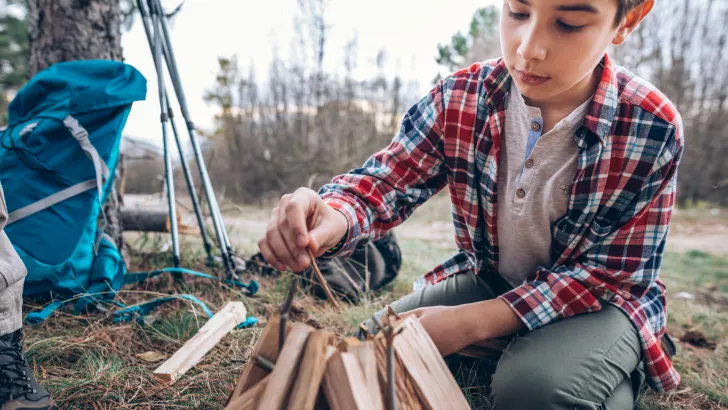 Boy building fire with campfire starter kit