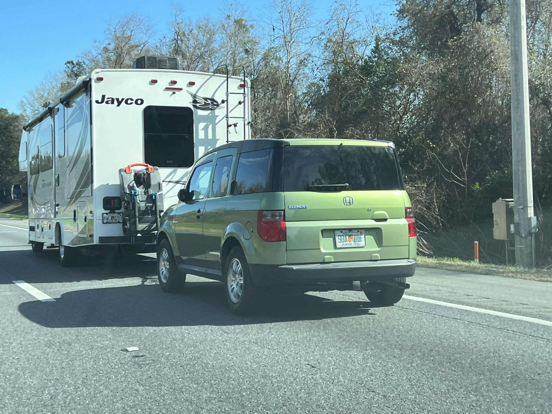 Green Honda Element being towed by RV