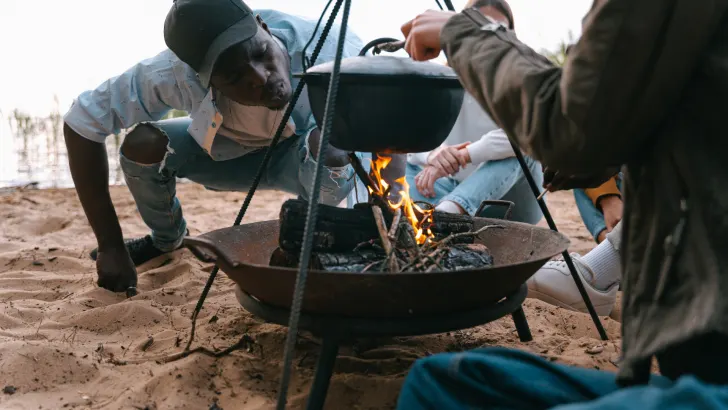 Man using campfire tripod to cook