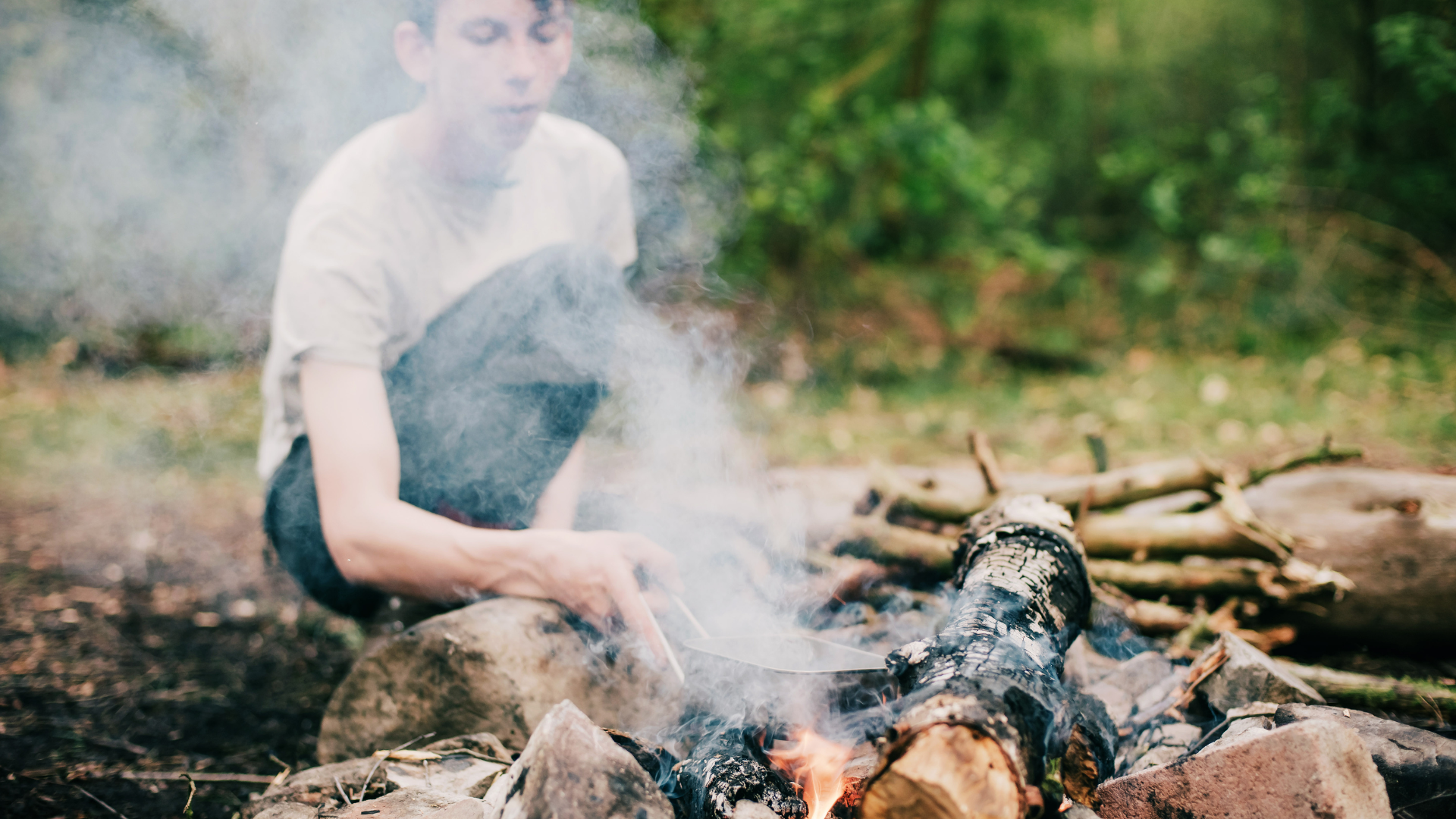 Boy building smoky campfire