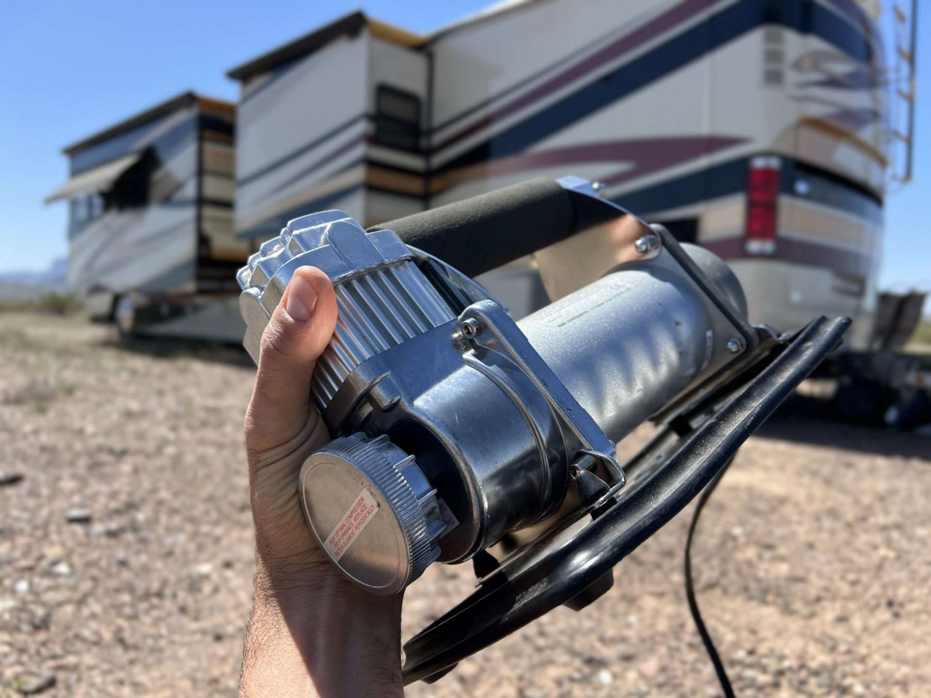 Portable air compressor being held up in front of an RV