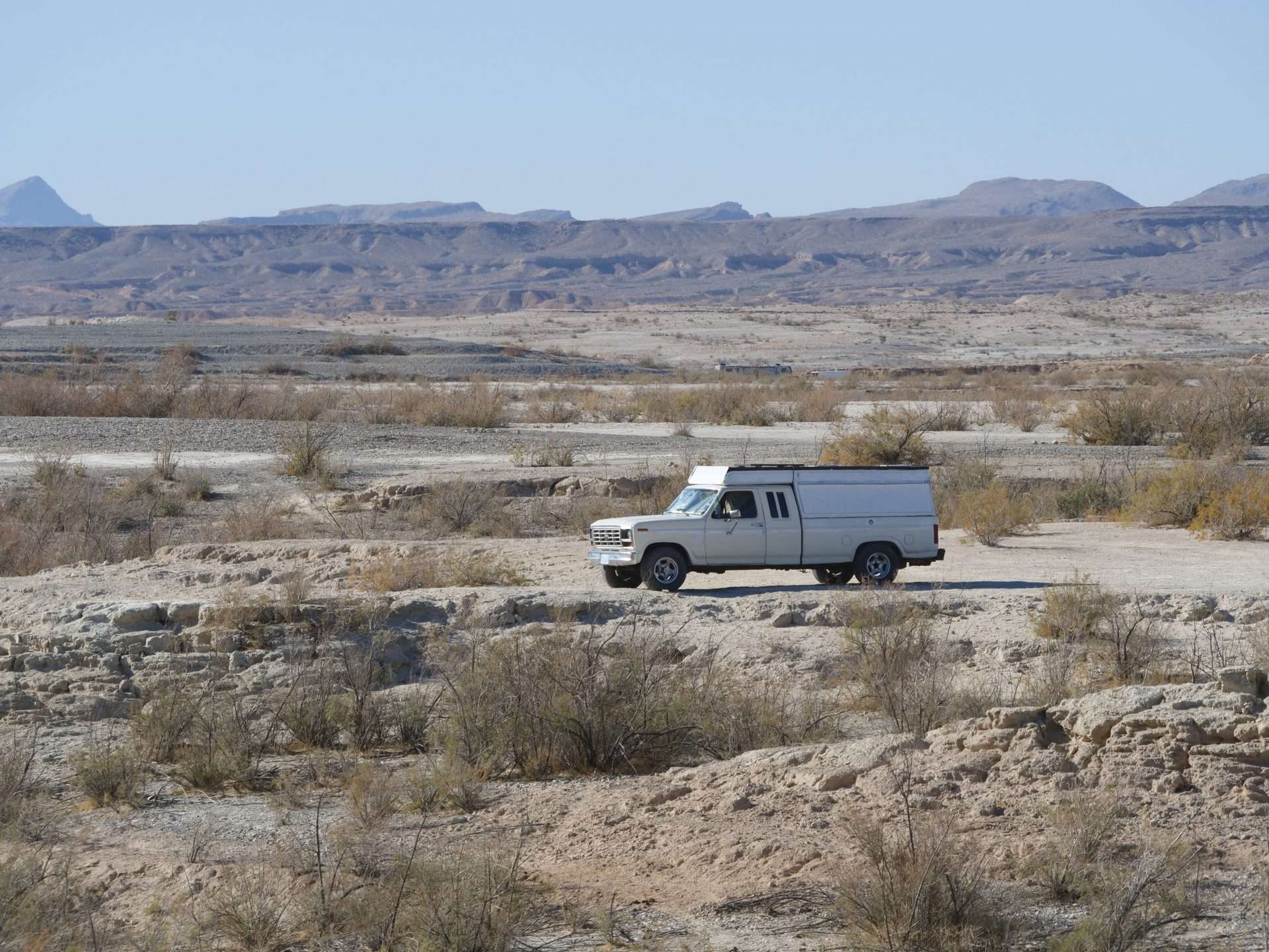 Truck with camping shell driving through desert