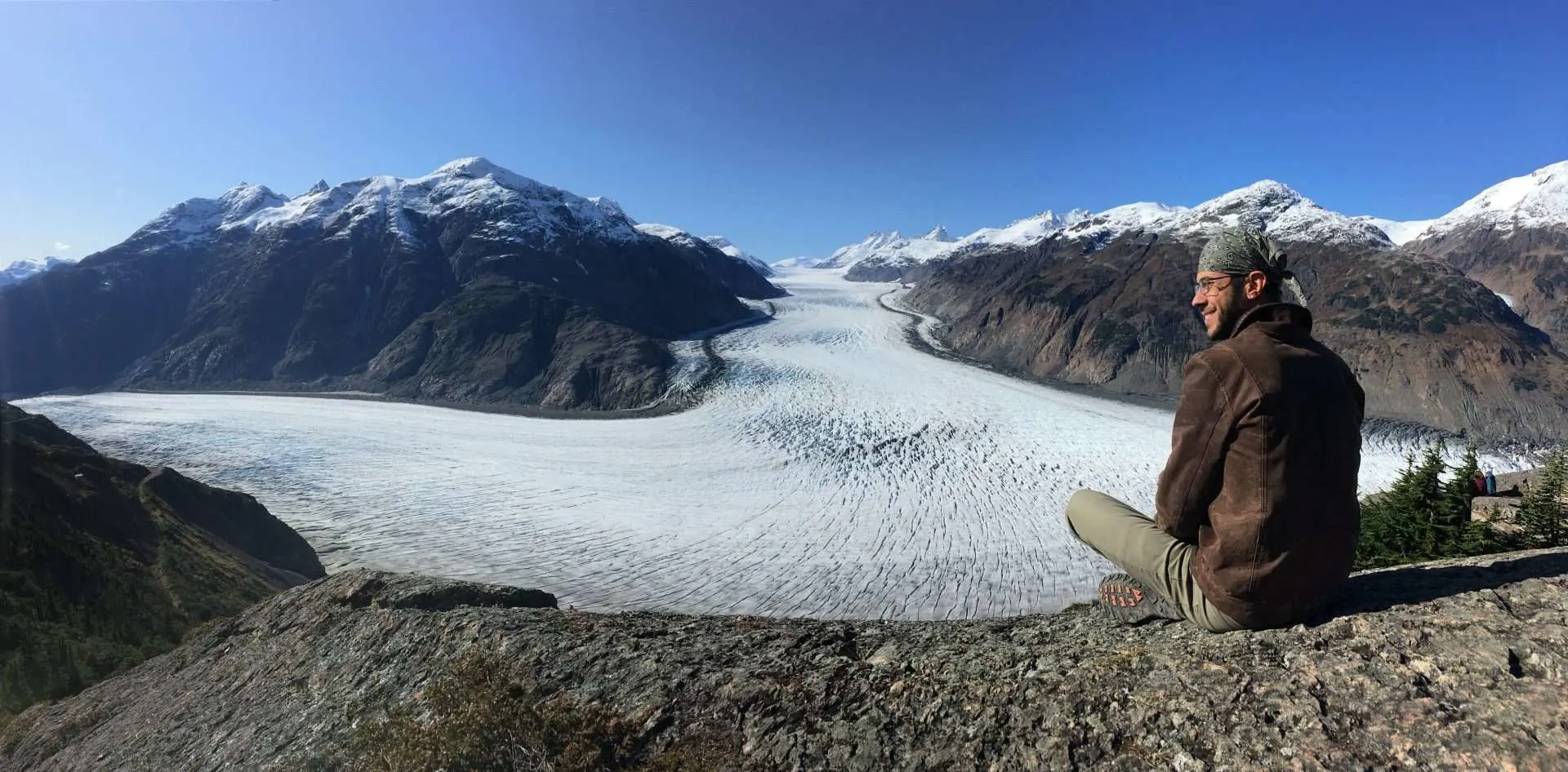 man sitting next to beautiful glacier