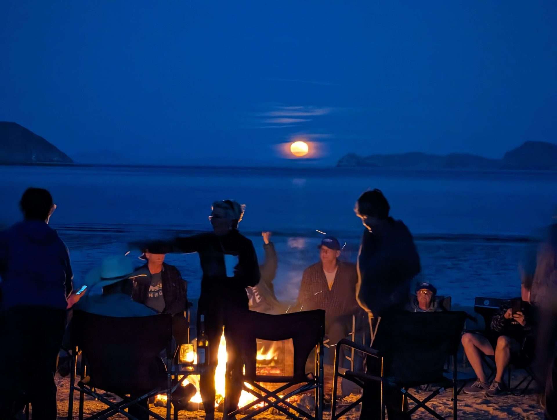 Friends around campfire at night